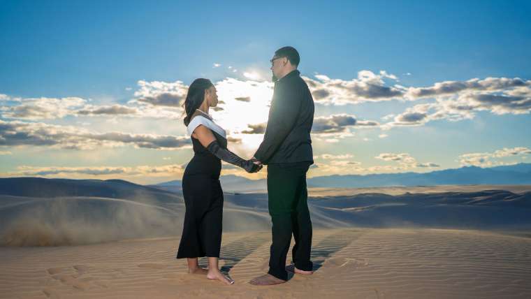Couple holding hands on the sand dunes under a wide open sky, Las Vegas engagement photography