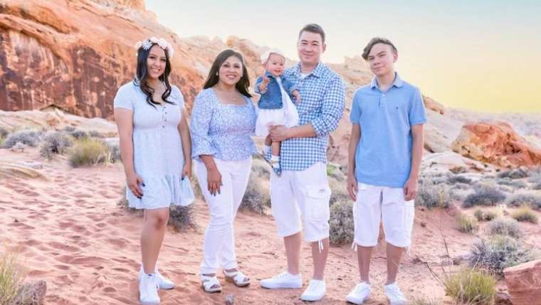 Family in white and blue posed among red rock formations, Las Vegas family photography session